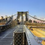 Brooklyn Bridge at dusk with glowing lights and pedestrians on the walkway—an iconic and free New York City experience.