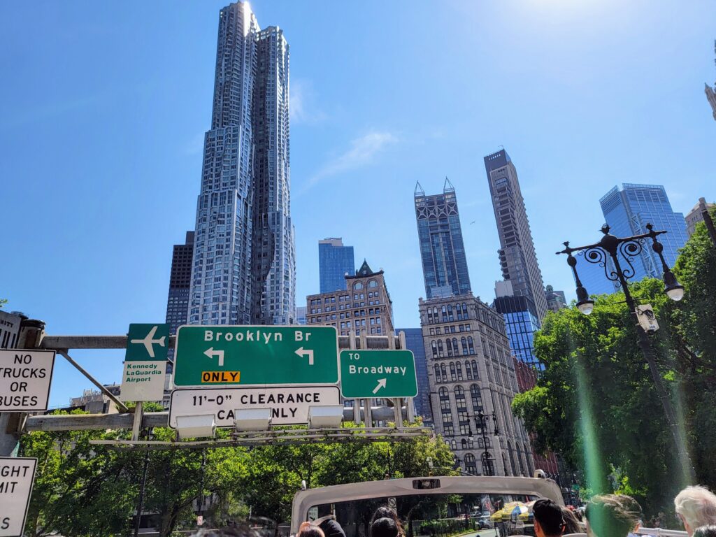 Street signs near Brooklyn Bridge directing to JFK Airport, Broadway, and Brooklyn—capturing the navigational charm of NYC’s infrastructure.