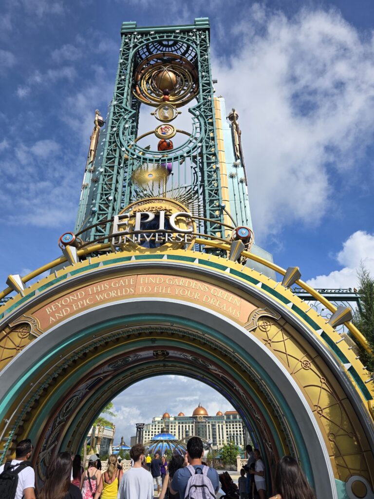 A colorful entrance archway to Universal's Epic Universe, with people walking underneath towards the park.