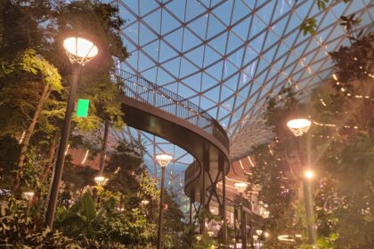 Indoor garden at Hamad International Airport featuring lush greenery, a geometric glass dome ceiling, and a curved elevated walkway—showcasing the best of Qatar’s airport design.