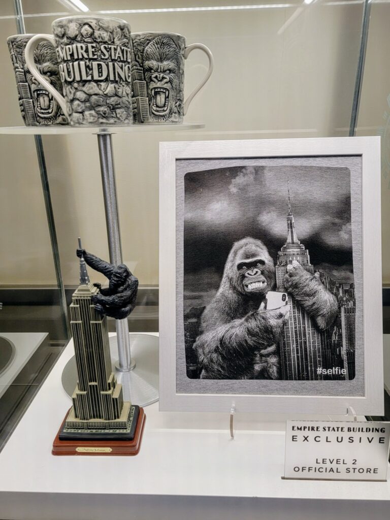 Display of Empire State Building-themed merchandise including mugs, figurines, and artwork featuring King Kong—blending pop culture with iconic NYC landmarks.