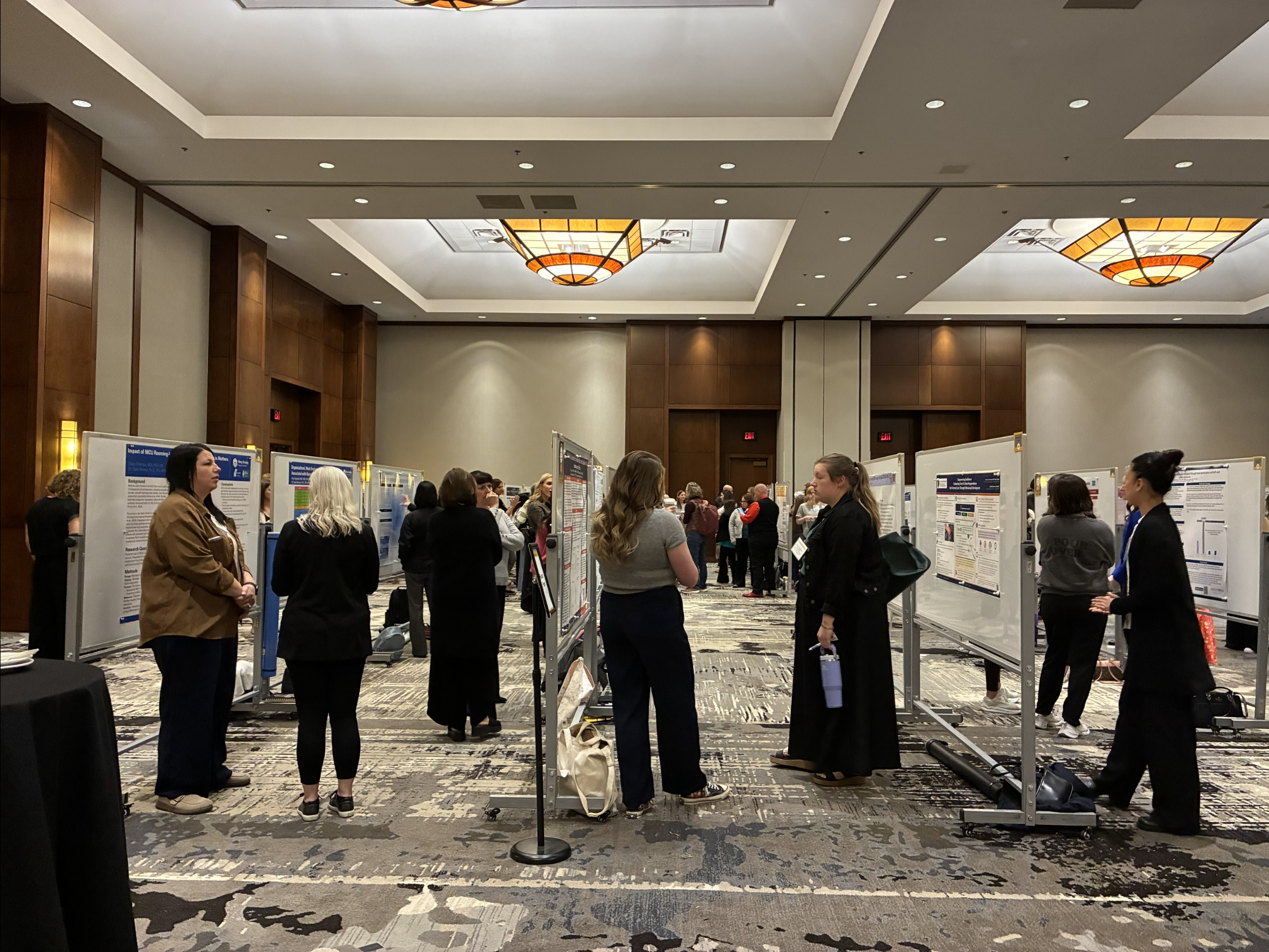 Poster presenters standing and engaging with viewers.